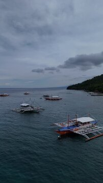 Outrigger boats off a forested island under storm clouds in Cebu
