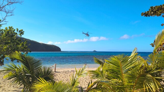 Scenic view idyllic tropical island with white sandy beach and turquoise ocean water and helicopter in Yasawa Islands, Fiji