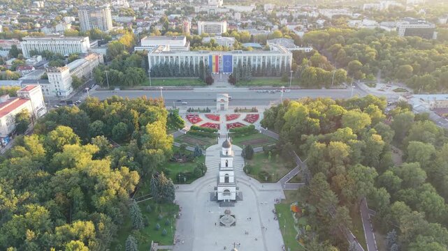 Aerial drone view of central Chisinau, Moldova, on a warm summer evening, featuring the Nativity Cathedral bell tower, Triumphal Arch, Cathedral Park, Government House and Moldova and European Union f