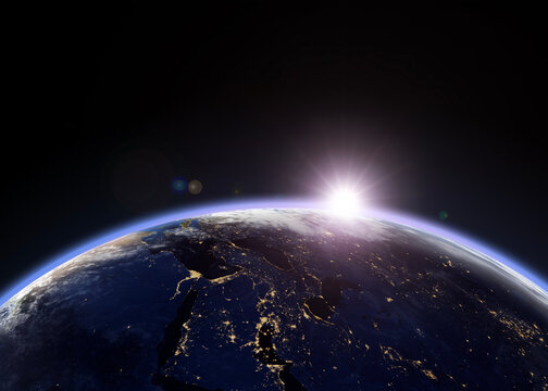 Earth and sunlight viewed from outer space, showing the planet&rsquo;s illuminated horizon and city lights across the night side.