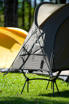 Off-ground tent cot on green grass at campsite.