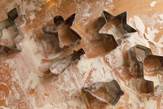 Baking tools and cookie cutters on a wooden table covered with flour