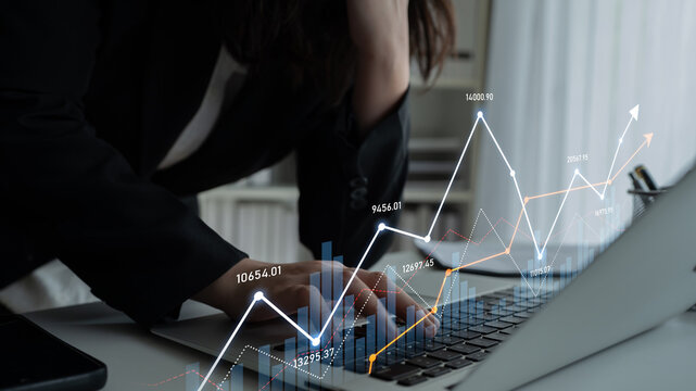 A business professional focuses on financial data using a laptop, showcasing growth charts and graphs that reflect stock performance in a sleek office environment. Scalp