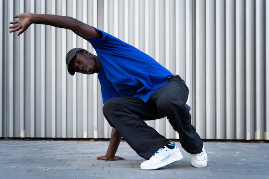 Male breakdancer performing street dance pose outdoors, showing flexibility and hip-hop culture style