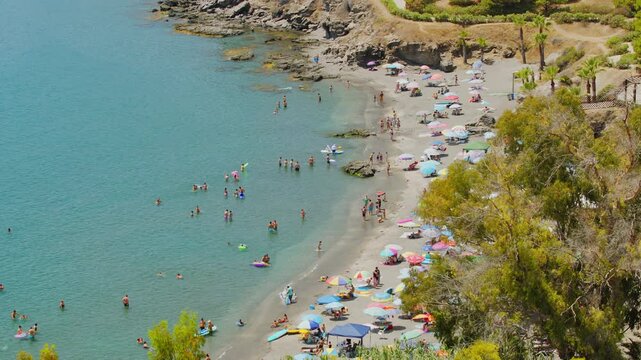 Scenic panoramic view of Costa Tropical coast in Almunecar, Spain. Beautiful Mediterranean sea bay crowded with tourists and vacationers relaxing on a sandy beach during summer holidays. 