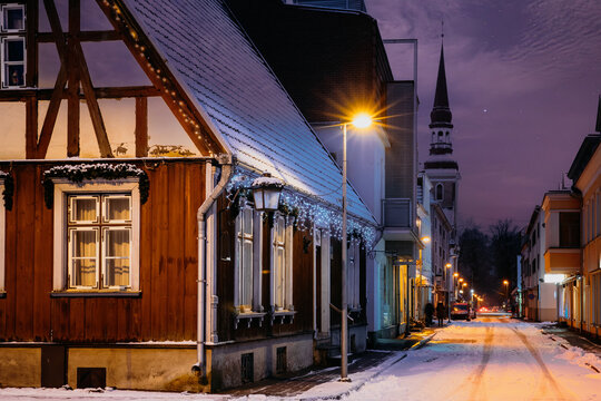 St. Elizabeth's Church and old wooden house on a snowy street in Parnu Old Town at winter night