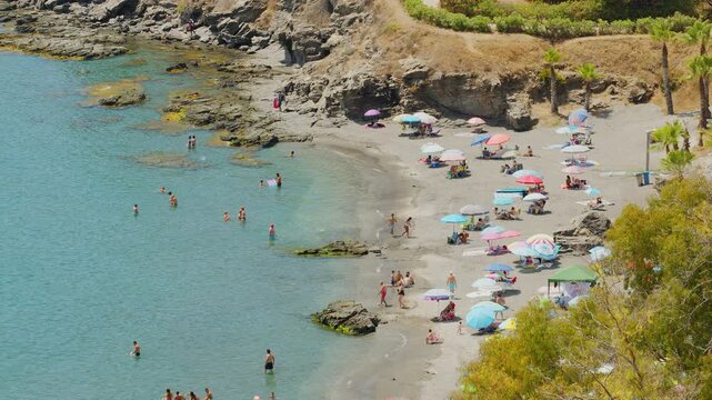 Scenic panoramic view of Costa Tropical coast in Almunecar, Spain. Beautiful Mediterranean sea bay crowded with tourists and vacationers relaxing on a sandy beach during summer holidays. 