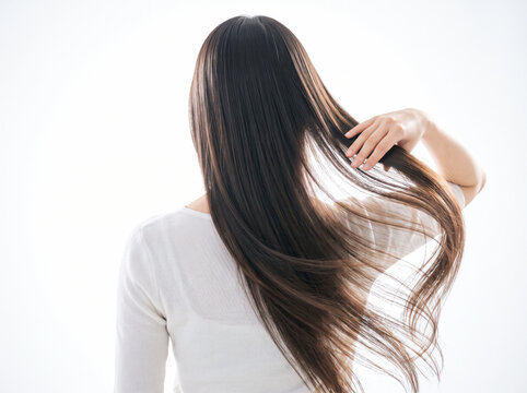 サラサラとした艶のある黒髪ロングヘアを手で触る女性の後ろ姿