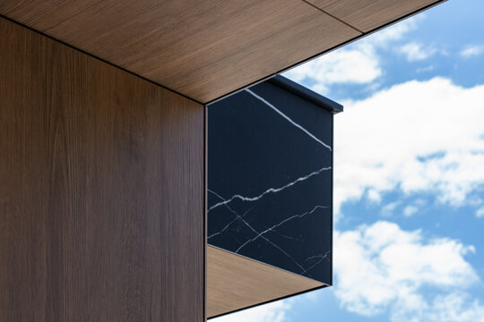 Luxury contemporary building exterior with wood paneling, dark stone finish and clean geometric lines, showcasing premium materials and modern architectural design