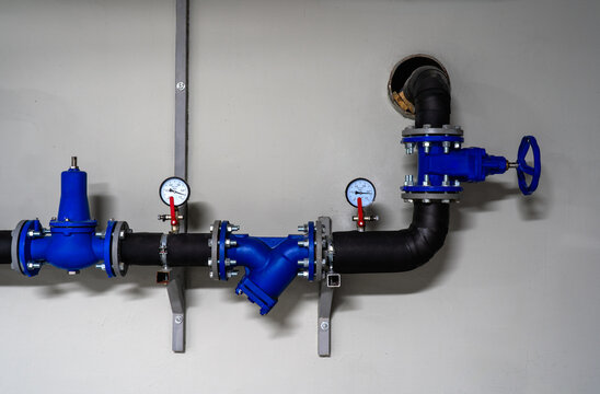 Modern building water supply system with blue industrial valves, pressure gauges, insulated pipes and filtration equipment