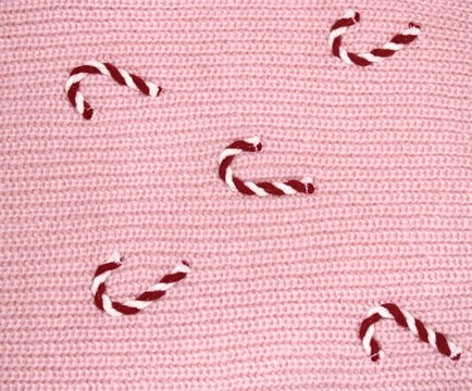 Candy canes scattered on a pink textured background during winter holidays for festive celebration