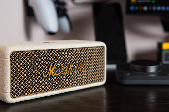 Macro close up of Marshall Emberton III cream wireless bluetooth speaker with brass logo on dark desk