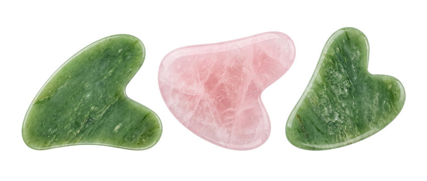 Gua sha stone facial massage tools set made of green jade and pink rose quartz crystal scrapers on black background for skincare routine spa treatment holistic wellness anti aging skin therapy