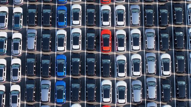 Aerial top‑down view of massive new car storage lot with neatly arranged vehicles	