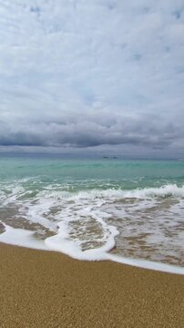 sea waves rolling on sandy shore under heavy cloudy sky. calm sea surf with foam washing beach in overcast autumn day. concept of sea background and relaxing screensaver with nature