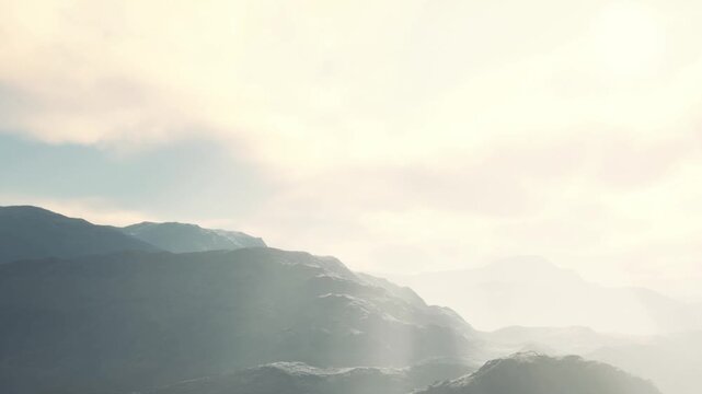 Mountains rise in the background as clouds float in the sky. Soft light shines on the landscape in the early morning. The scene shows nature in a simple and clear way.
