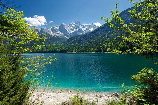 Travel landscape of Zugspitze Alps in Bavaria, Germany, scenic summer nature panorama with forest, Eibsee lake, snow mountains peak. Alpine landscape