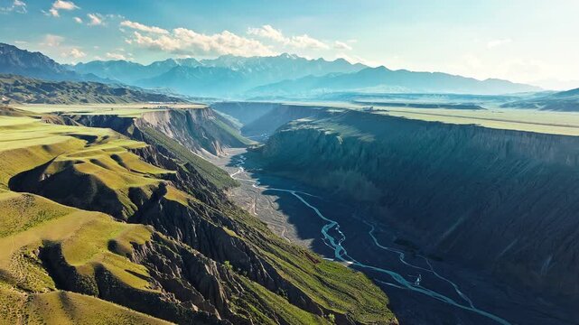 Aerial view of a winding braided river flowing through a deep rocky canyon under a clear blue sky in Anjihai Grand Canyon, Xinjiang, China