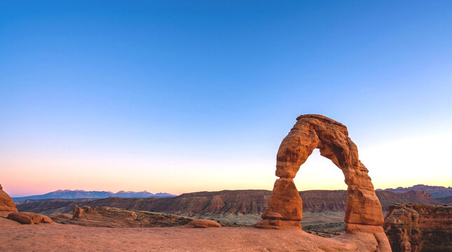 Delicate sandstone arch rock formation at sunset horizon desert landscape