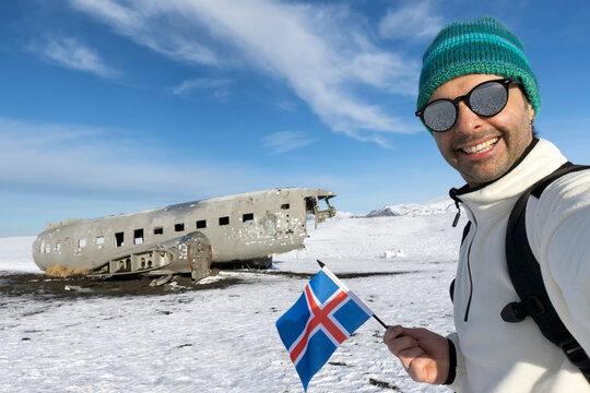 Selfie of a tourist man at the crashed plane on the frozen Solheimasandur beach in winter in Iceland