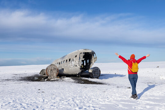 A tourist  walking on the crashed plane on the frozen Solheimasandur beach in winter in Iceland
