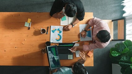 Obraz na płótnie Canvas Manager talking to boss by using phone while diverse team sharing idea or financial chart in tablet. Top view of diverse people brainstorming and sharing plan while man talking to phone. Convocation.