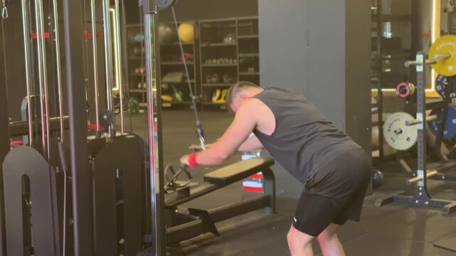 A focused video of an athletic man performing straight arm lat pulldowns on a cable machine, demonstrating back muscle activation, upper body strength, and proper workout form.