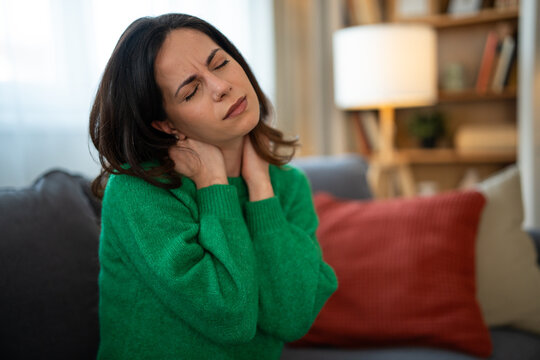 Woman experiencing severe neck pain and discomfort at home