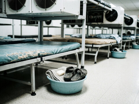 Empty military barracks or dormitory room with metal beds, personal items in a basin