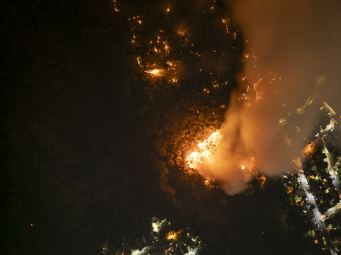 Aerial view of the Uruapan wildfire burning through the forest at night with bright flames and smoke plumes rising near the illuminated residential area of Uruapan, Michoacan, Mexico.