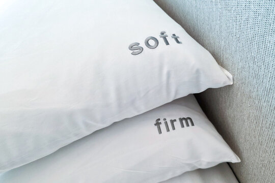 Close-up on firm and soft pillow alternatives placed on bed for hotel room guests to choose in accordance to preference for a comfortable sleep