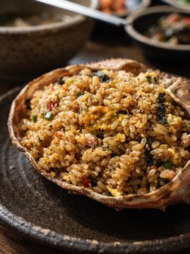 Macro close up of shiny crab tomalley fried rice grains inside crab shell.