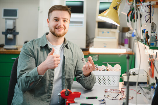 Optician smiling and giving thumbs up holding repaired eyeglasses