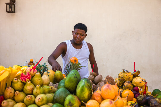 Young vendor arranging tropical fruit at a stall, Cartagena, Colombia