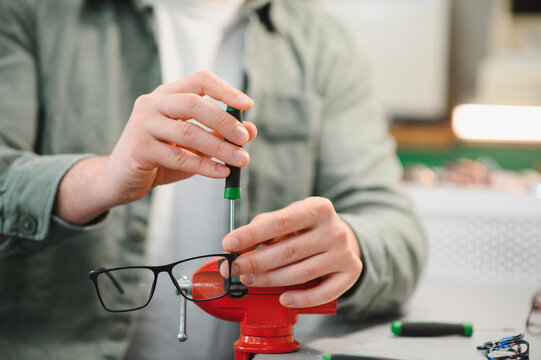 Optician repairing eyeglasses using screwdriver and vise