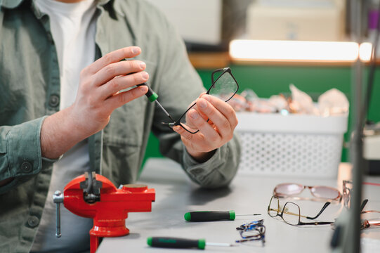 Person repairing optical frame with precision screwdriver
