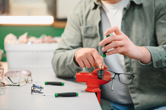 Optician hands repairing eyeglasses with precision tools