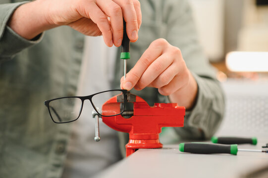 Technician repairing optical glasses using precision screwdriver