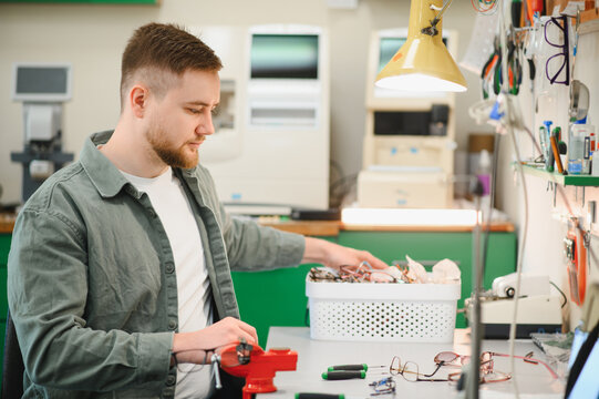 Man repairing glasses in optics workshop