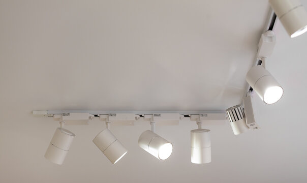 Modern ceiling track lighting features several adjustable spotlights mounted on a white ceiling, providing illumination in a contemporary interior setting