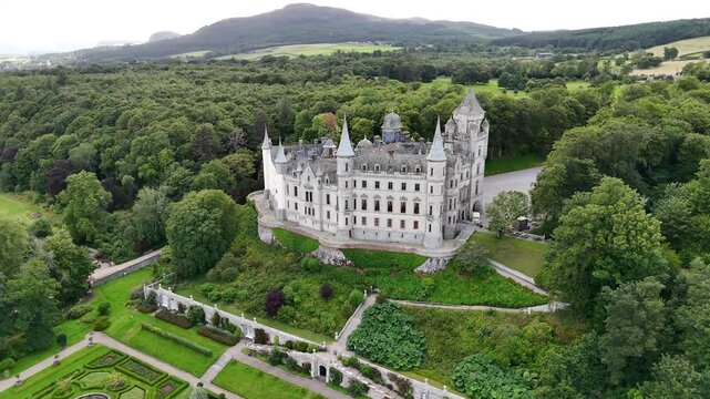 Establishing drone footage of Dunrobin Castle chateau in Golspie, showing iconic conical turrets, Sir Charles Barry designed gardens, and coastal horizon in Sutherland Scotland
