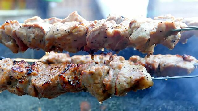 Close-up shot of juicy pork shish kebab skewers grilling over hot charcoal briquettes with glowing embers and small flames. Perfect for summer barbecue, outdoor cooking, food background, and picnic co