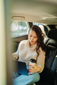Woman working on laptop while traveling in car