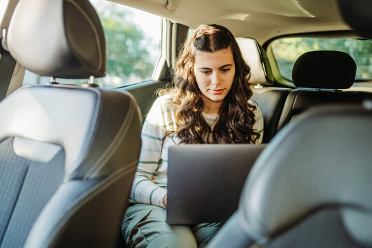 Young woman working on laptop in car