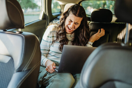 Woman experiencing stress while working on laptop in car