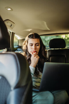 Woman working on laptop while commuting in car