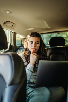 Young woman thinking while remote working in car