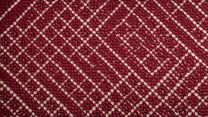 Fototapeta premium Red cross-stitch embroidery pattern on beige fabric background texture