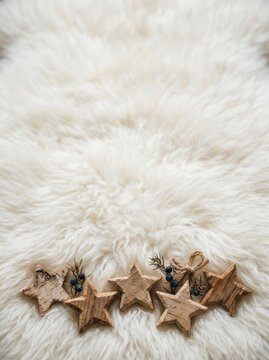 Carved wooden star ornaments arranged in a lower border across fluffy white sheepskin fleece fur.