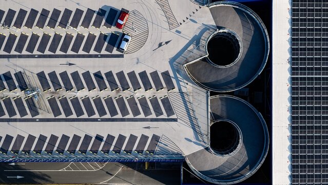 Aerial view of a modern parking garage featuring spiral ramps, marked parking spaces, and solar panels on the roof in Delft, South Holland, Netherlands.
